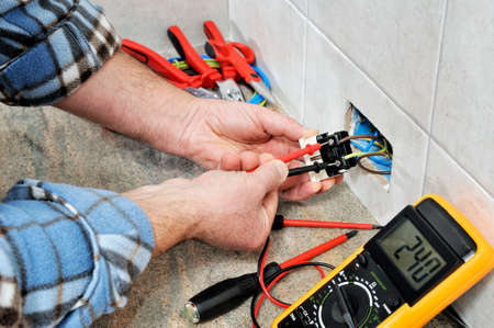 Electrician technician at work measures the voltage of a residential electrical system.の写真素材
