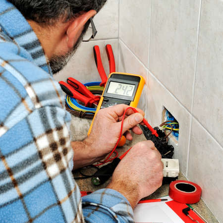 Electrician technician at work measures the voltage of a residential electrical system.の写真素材