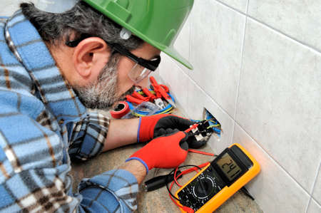 Electrician technician with gloves and safety instruments he measures the voltage of a residential electrical system.の写真素材