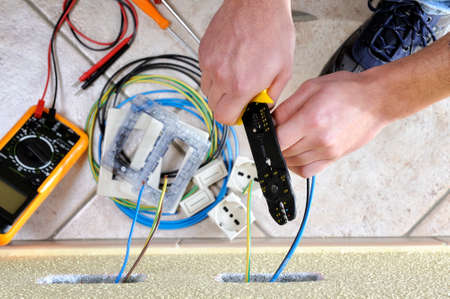 Electrician technician at work uses the wire stripper in a residential electrical installationの写真素材