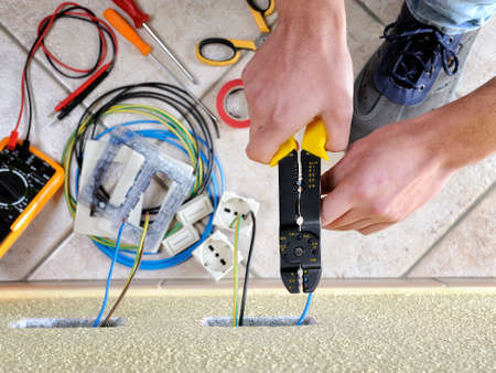 Electrician technician at work uses the wire stripper in a residential electrical installationの写真素材