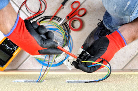 Electrician technician at work blocks the cable between the clamps of a socket in a residential electrical installationの写真素材