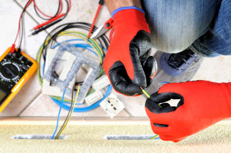 Electrician technician at work prepares the cable with hands protected by gloves in a residential electrical installationの写真素材