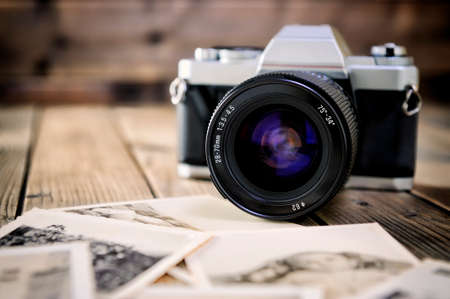 Close up of vintage photographic prints, film camera and on a rustic wooden table.の写真素材