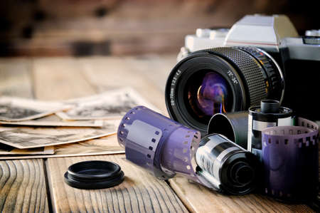 Close-up of 35mm films, vintage photographic prints, camera film and on a rustic wooden table.