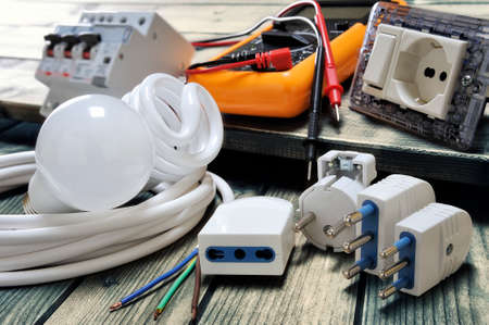 Close up of plugs and sockets and other components for residential electrical installation on rustic wooden tableの写真素材