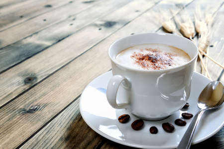 Close-up of a cup of coffee with milk on an antique wooden table.の写真素材