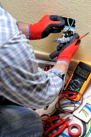 Electrician technician at work sticks the cable between the clamps of a socket in a residential electrical installation. Vertical orientation.の写真素材