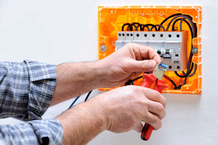 Electrician technician working on a residential electric panel, cuts the cable with a cable cutterの写真素材
