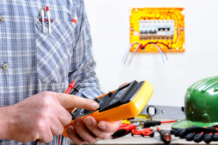 Electrician technician at work in a residential electric installation, turn on the testerの写真素材