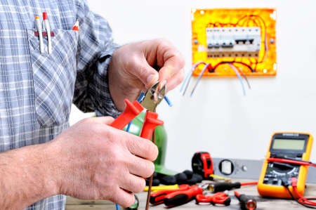 Electrician technician at work in a residential electric installation, cuts the cableの写真素材