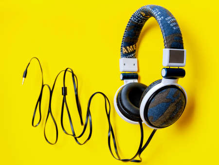 Top view of an audio headphone covered with fabric jeans photographed on a yellow backgroundの写真素材