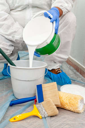 House painter at work pours white paint into a containerの写真素材