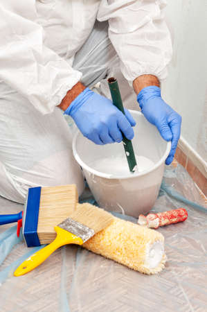 House painter at work mixes paint and water in a containerの写真素材