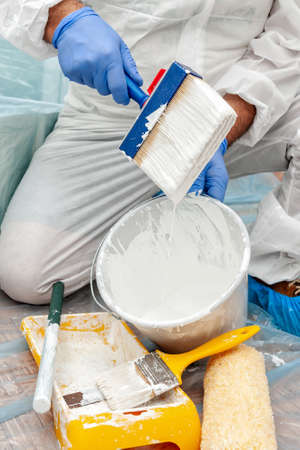 Close-up of a house painter's hand at work while he prepares white paintの写真素材