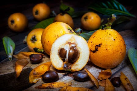 Close-up of freshly harvested fresh medlars on an antique wooden table, photographed in light paintingの写真素材