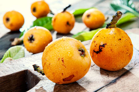 Close-up of freshly harvested fresh medlars on an antique wooden table.の写真素材