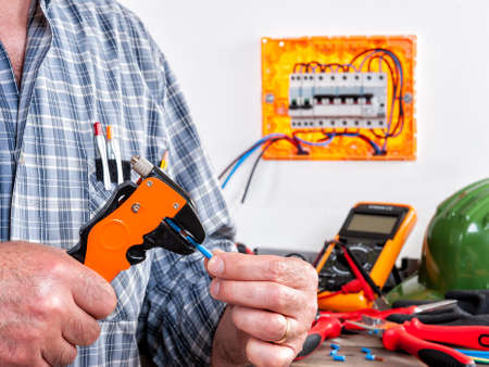 Electrician technician at work with wire stripper on cables in a residential electrical installation.の写真素材