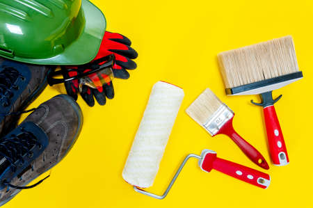 Top view of work tools and safety equipment for professional house painter on a yellow deskの写真素材