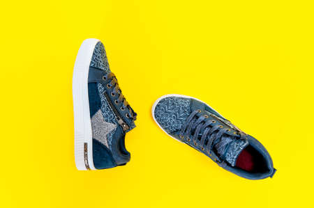 Top view of girl's shoes for leisure photographed on yellow background.