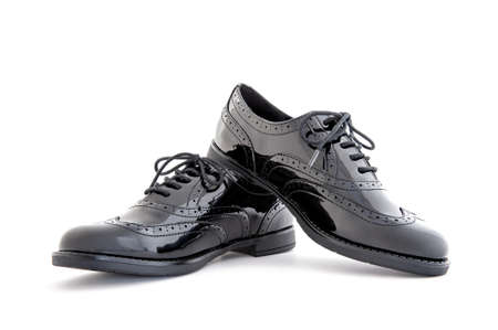 Close up of beautiful girl's elegant black leather shoes photographed on white background.の写真素材