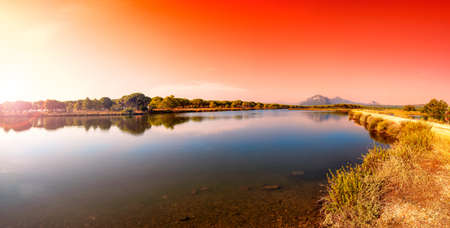 Beautiful landscape at sunrise of a pond with the reflection of the trees and the sky on the water. Petrosu pond, Orosei. Sardinia.の写真素材