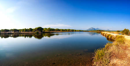 Beautiful landscape of a pond with the reflection of the trees and the sky on the water. Petrosu pond, Orosei. Sardinia.の写真素材