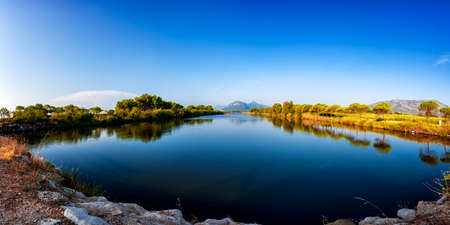 Beautiful landscape of a pond with the reflection of the trees and the sky on the water. Petrosu pond, Orosei. Sardinia.の写真素材