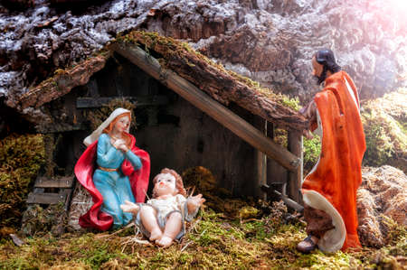 Close-up of the Christmas Nativity scene. Hut with baby Jesus in the manger, with Mary and Joseph. Ray of light.の写真素材