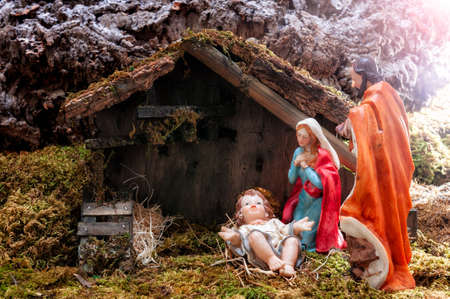 Close-up of the Christmas Nativity scene. Hut with baby Jesus in the manger, with Mary and Joseph. Ray of light.の写真素材