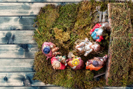 Top view of the Christmas Nativity scene. Hut with baby Jesus in the manger, with Mary, Joseph and the three wise men. On a vintage wooden table.の写真素材