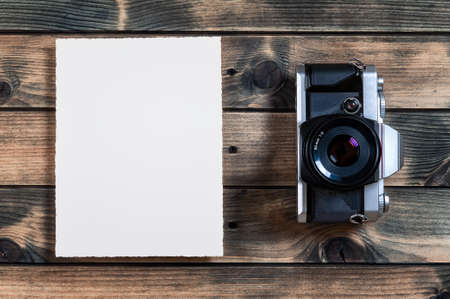Top view of an old 35mm camera on a rustic wooden table. White space for text.