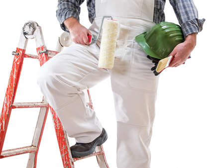 House painter worker on the ladder with white work overalls, keeps the roller to paint in his hand. Equipped with shoes, helmet and protective gloves. Isolated on white background.の写真素材