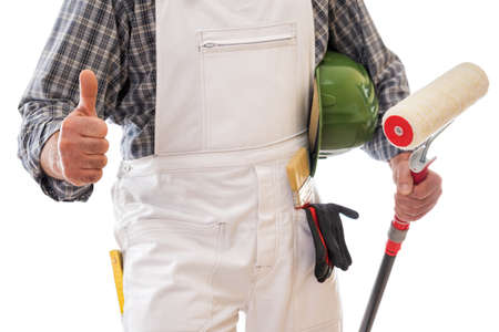 House painter worker in white work overalls with thumb up, holds in his hand the roller to paint. Equipped with protective gloves. Isolated on white background. Construction industry.の写真素材