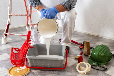 Caucasian worker house painter at work, preparing the paint for painting the wall. Construction...