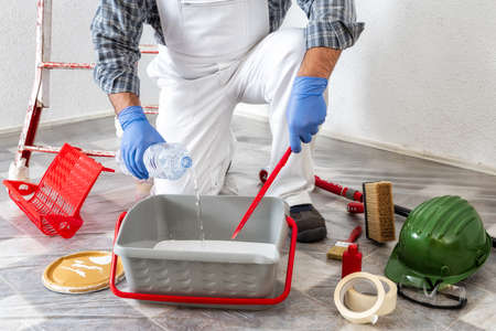 Caucasian worker house painter at work, preparing the paint for painting the wall. Construction industry.の写真素材