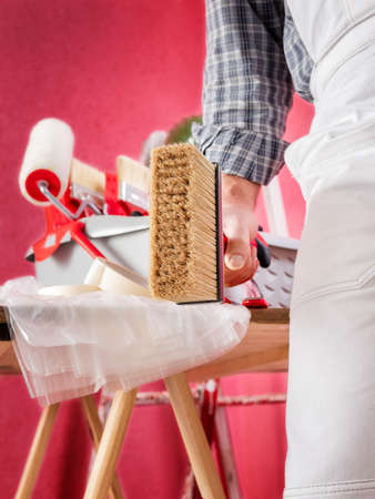 Caucasian house painter worker in white work overalls, holds the brush to paint with your hands....