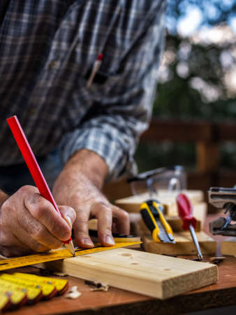 Adult carpenter craftsman with a pencil and the carpenter's square trace the cutting line on a...