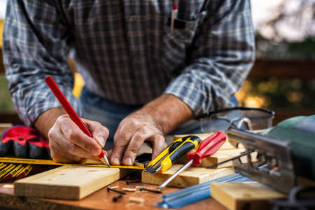 Adult carpenter craftsman with a pencil and the carpenter's square trace the cutting line on a wooden table. Construction industry, housework do it yourself. Stock photography.の写真素材
