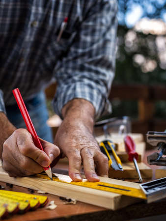 Adult carpenter craftsman with a pencil and the carpenter's square trace the cutting line on a wooden table. Construction industry, housework do it yourself. Stock photography.の写真素材