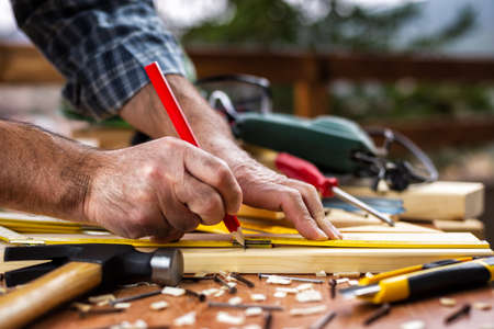 Adult craftsman carpenter with the meter measuring a wooden table. Construction industry, housework do it yourself. Stock photography.の写真素材