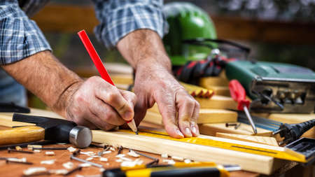 Adult carpenter craftsman with a pencil and the carpenter's square trace the cutting line on a wooden table. Construction industry, housework do it yourself. Stock photography.の写真素材