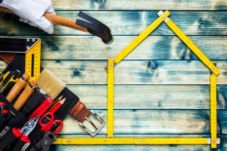 Top view of a hand protected by leather work gloves that holds the carpenterâ€™s hammer on an...