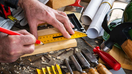 Top view. Carpenter with pencil and the carpenter's square draw the line on a wooden board. Construction industry, do it yourself. Wooden work table.の写真素材