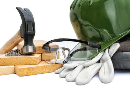 Close-up of a carpenter's hammer, helmet, goggles and protective gloves on a white background. Industry construction, work safety.の写真素材