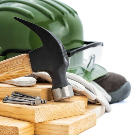 Close-up of a carpenter's hammer, helmet, goggles and protective gloves on a white background. Industry construction, work safety.の写真素材