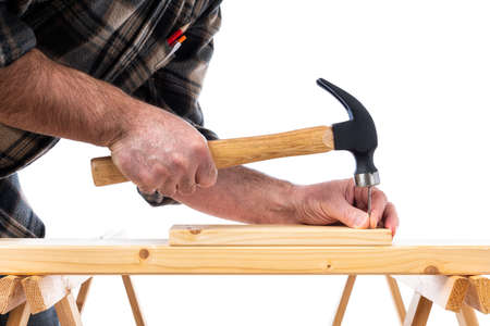 Close-up. Carpenter with hammer and nails fixes a wooden board. Construction industry, do it yourself. White background.の写真素材