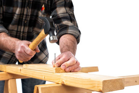 Close-up. Carpenter with hammer and nails fixes a wooden board. Construction industry, do it yourself. White background.の写真素材