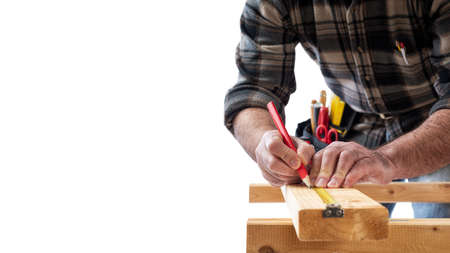 Close-up. Carpenter with pencil and the meter marks the measurement on a wooden board. Construction industry. White background.の写真素材