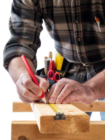 Close-up. Carpenter with pencil and the meter marks the measurement on a wooden board. Construction industry. White background.の写真素材